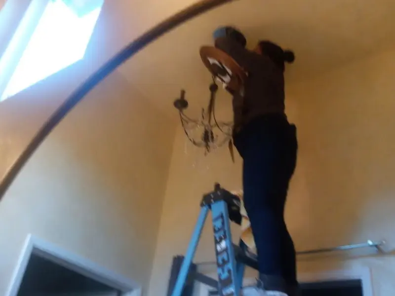 Electrician installing a chandelier in a Lucerne Valley residence